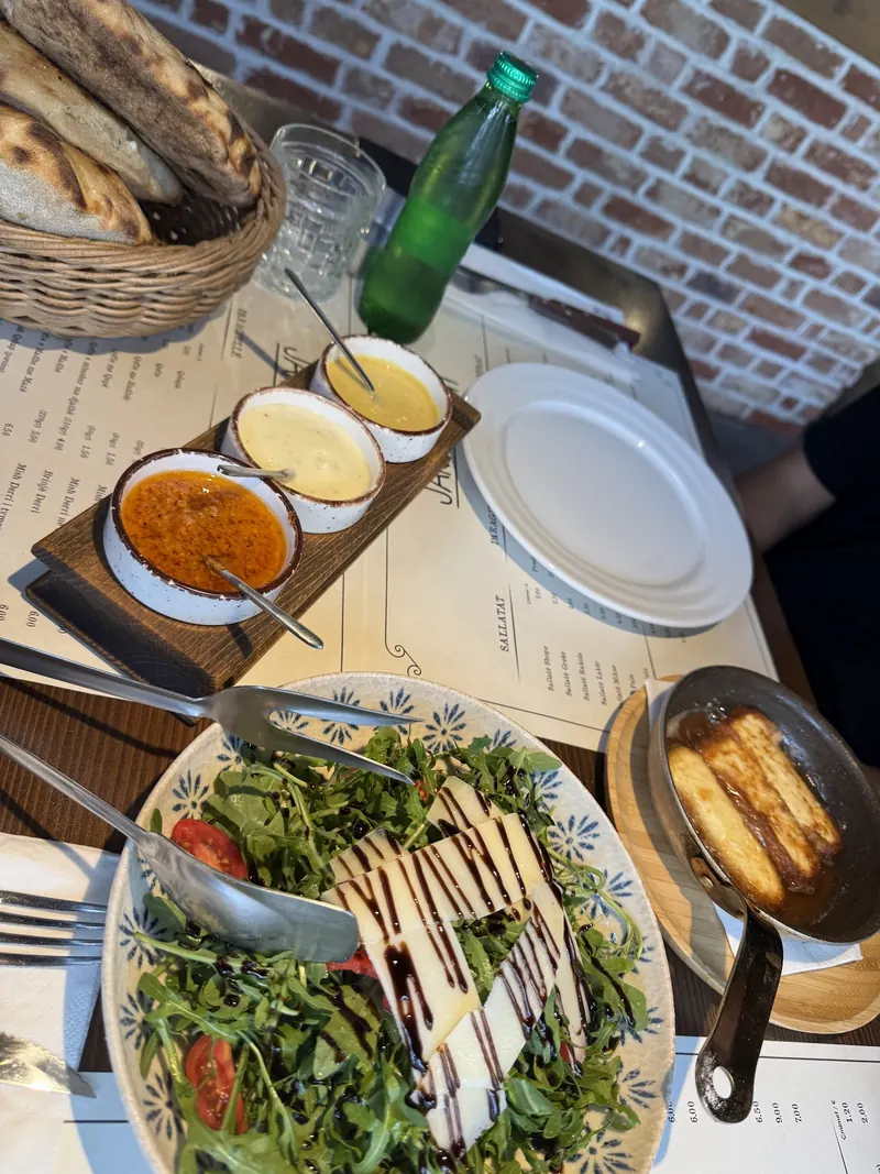 A rocket salad with cheese and balsamic, sauces and bread on a table by the brick wall