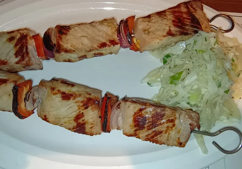 Two pork skewers with peppers and a cabbage salad