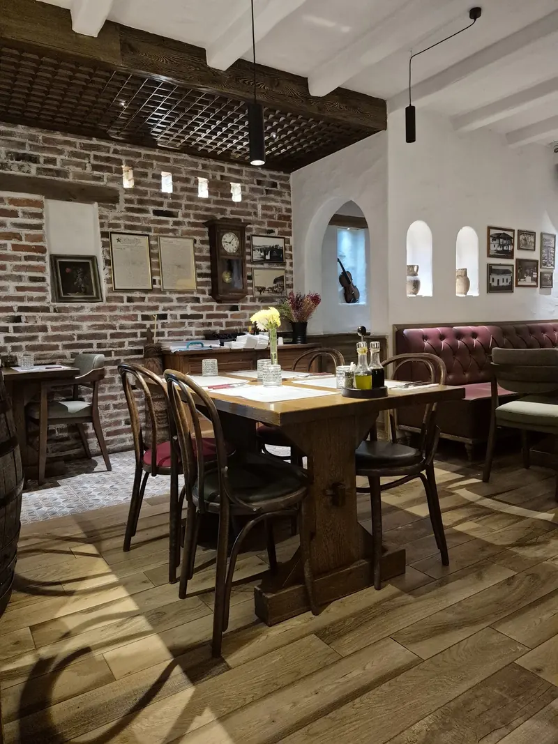 A corner of the dining room with a brick wall, a wall clock and set tables